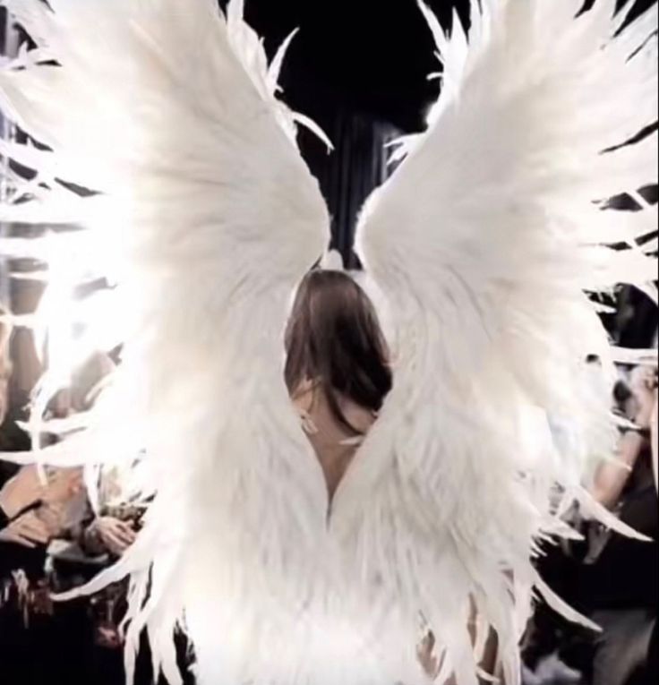 a woman with white wings standing in front of a mirror