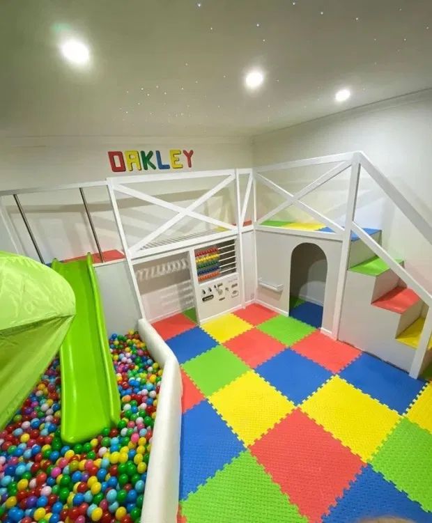 an indoor play area with lots of colorful balls and plastic blocks on the floor, including a slide