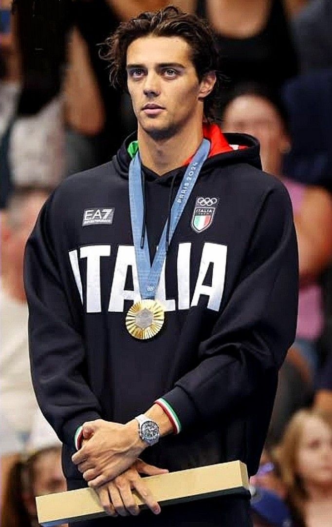 a male tennis player with a medal around his neck and wearing a black hoodie