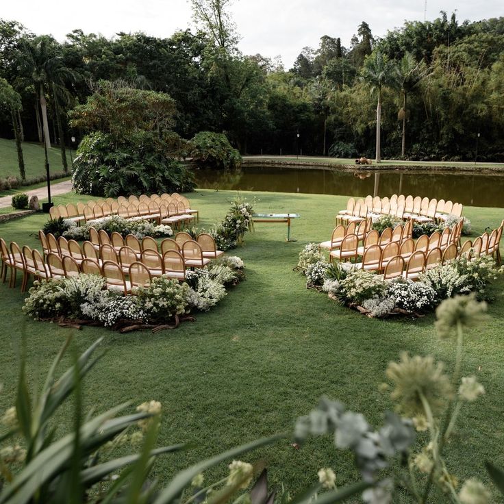 rows of chairs set up in the middle of a field with flowers and greenery