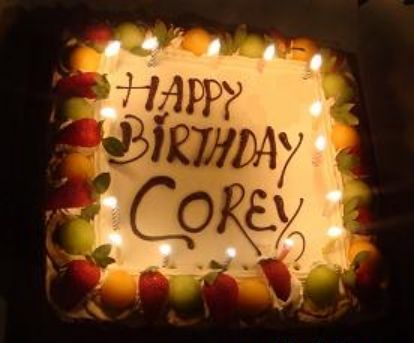 a birthday cake with candles and fruit on it that says happy birthday corey,