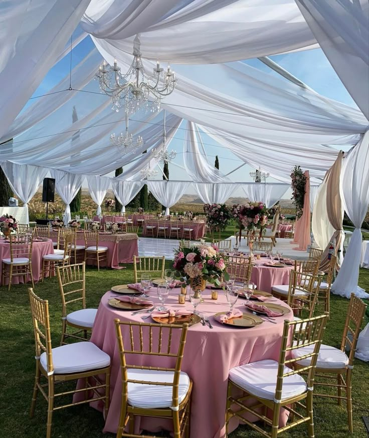 the tables are set up with pink linens and white draping over them