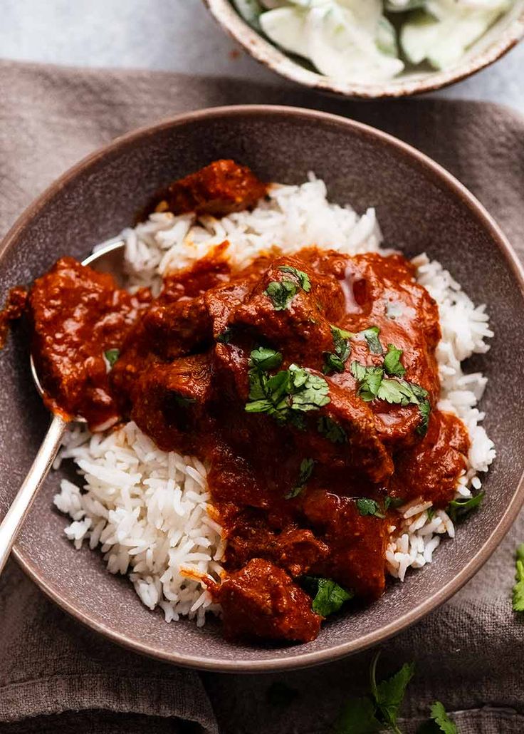 a bowl filled with rice and meat covered in sauce