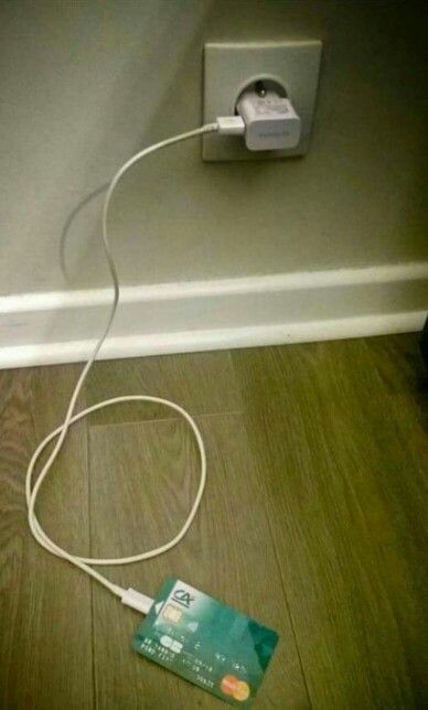 an electronic device plugged into a wall with a charger on the ground next to it