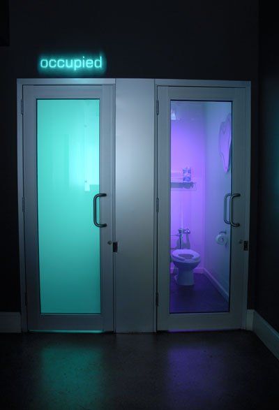 the bathroom is lit up with purple light and has two doors that lead into it