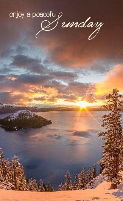 the sun is setting over a lake with snow on it and trees in the foreground