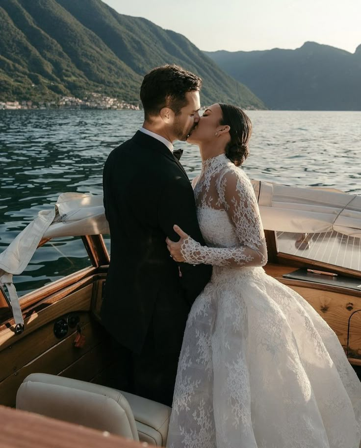 a bride and groom kissing on the back of a boat