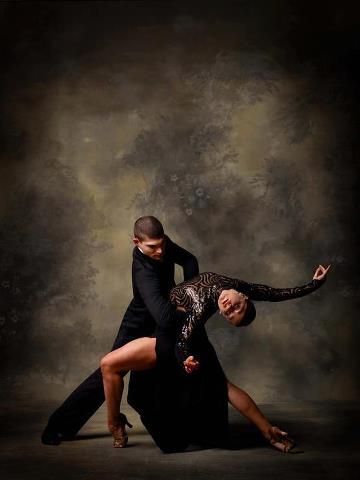 two people are dancing in the dark with one holding the other's leg up