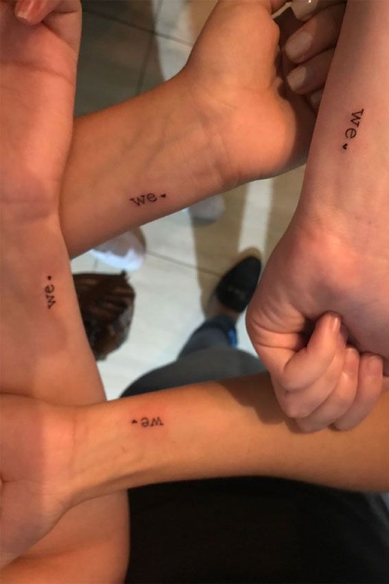 three people holding hands with small tattoos on them