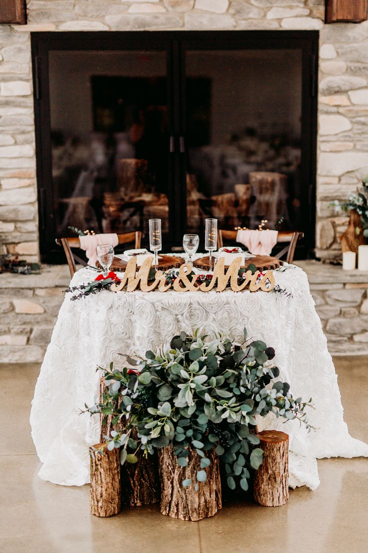 the table is set up for a wedding reception with greenery and wooden letters on it