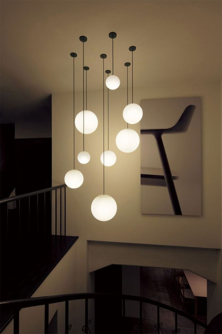 a bunch of lights hanging from the ceiling in a room with stairs and railings