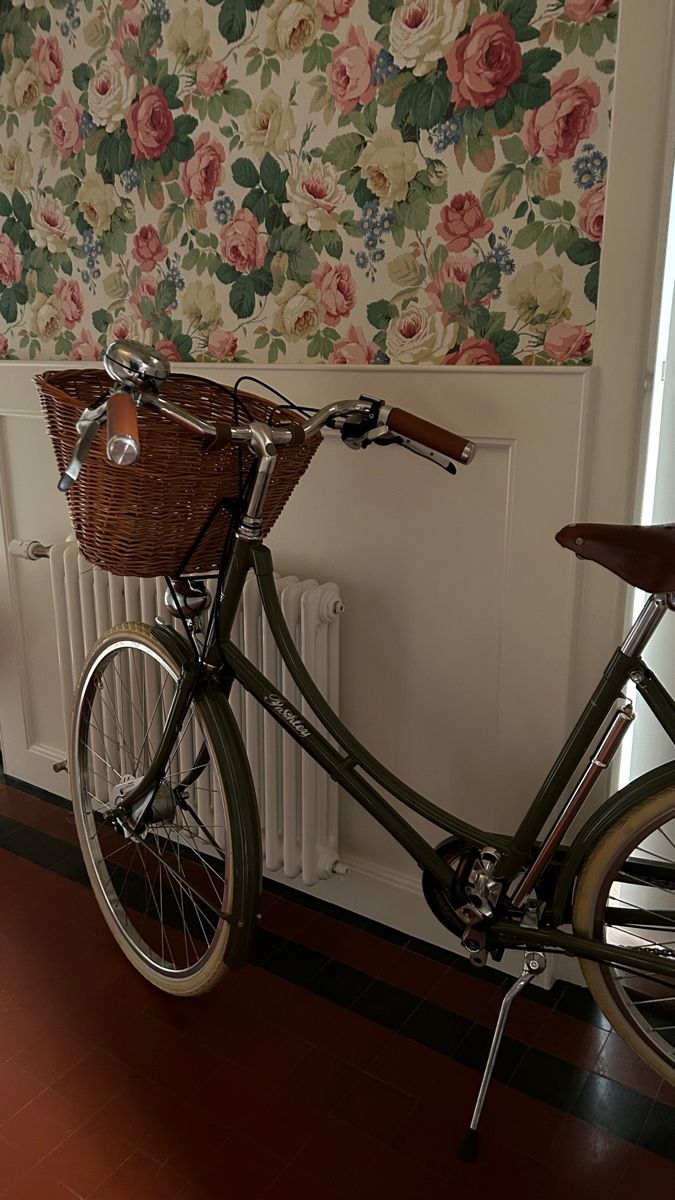 a bicycle parked in front of a wall with flowers on it and a radiator