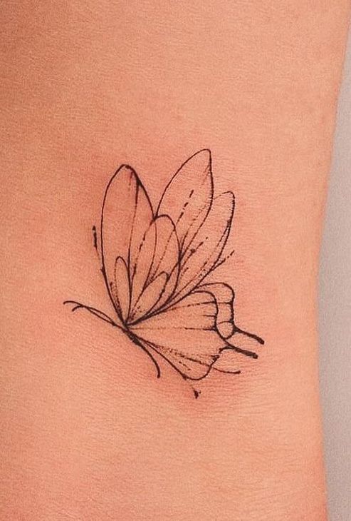 a small butterfly tattoo on the side of a woman's rib - up stomach