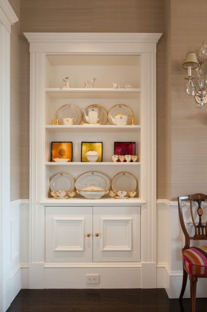 a white china cabinet with plates and cups on it's shelves in a dining room