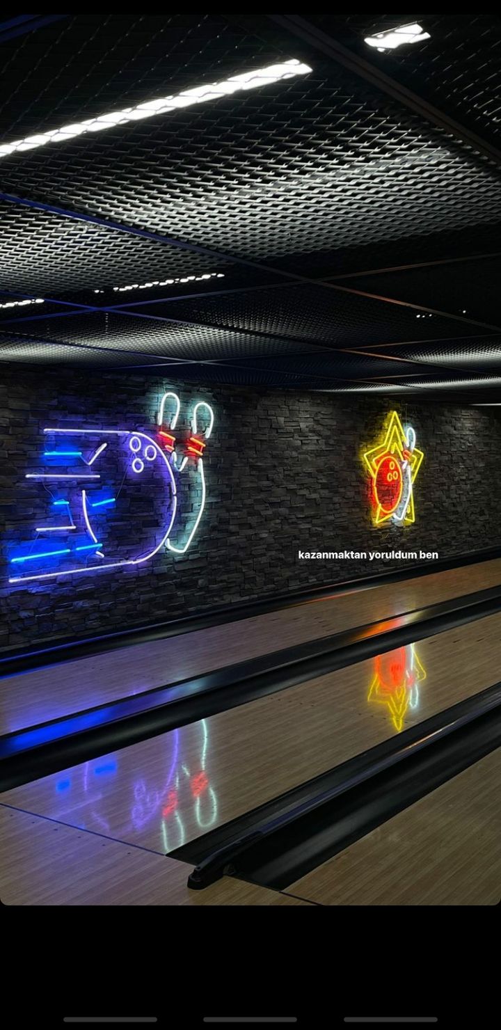 the bowling alley is decorated with neon lights and animated characters on the wall behind it