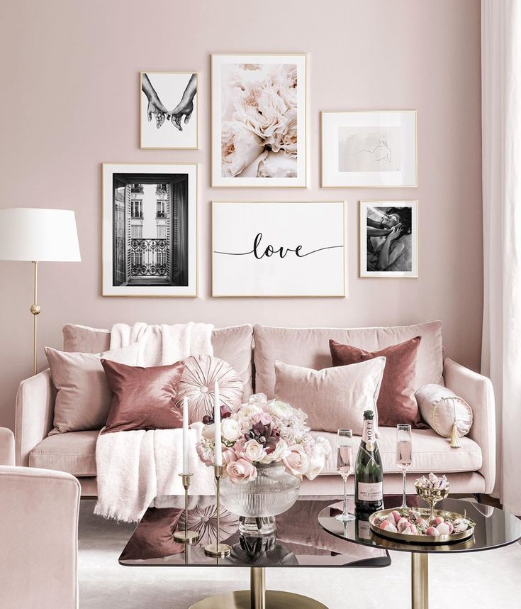 a living room with pink walls and pictures on the wall above the couch, coffee table