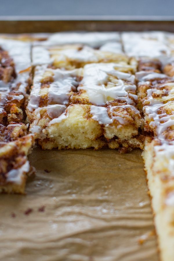 cinnamon roll with icing sitting on top of a wooden cutting board