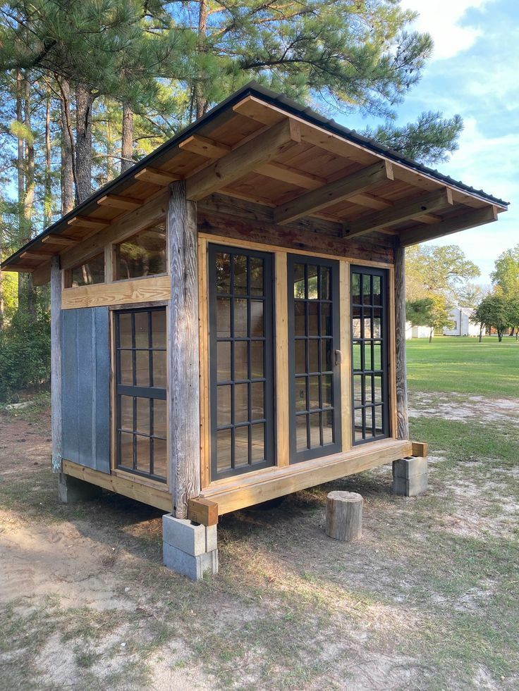 a small wooden structure with windows in the grass