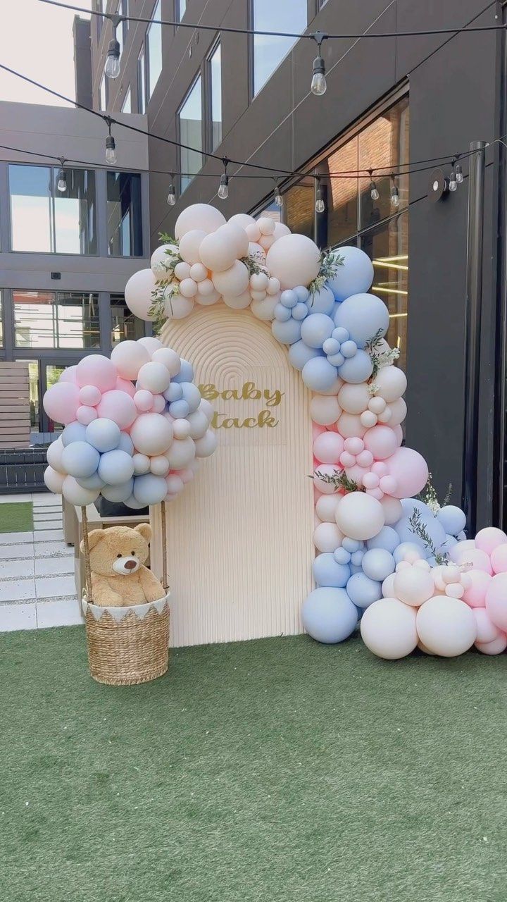 a teddy bear and balloon arch in front of a building