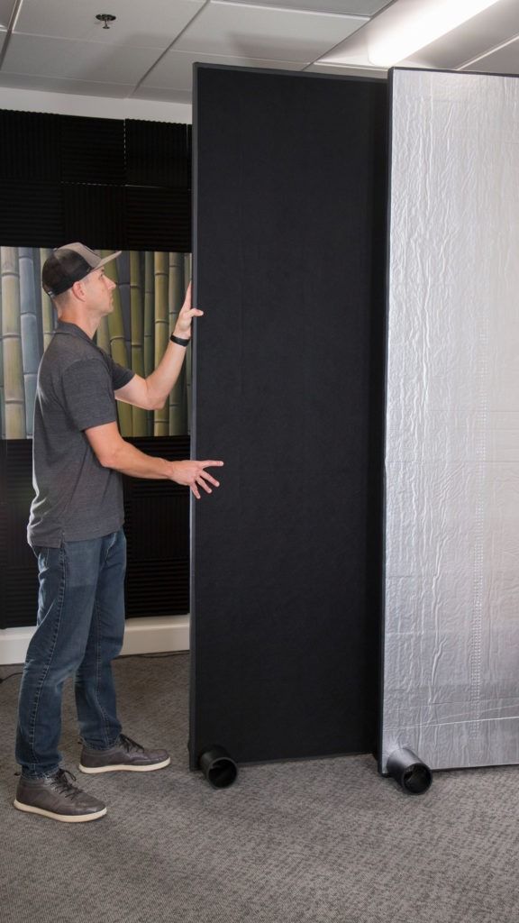 a man standing in front of two black and white partitions with one person pointing at it