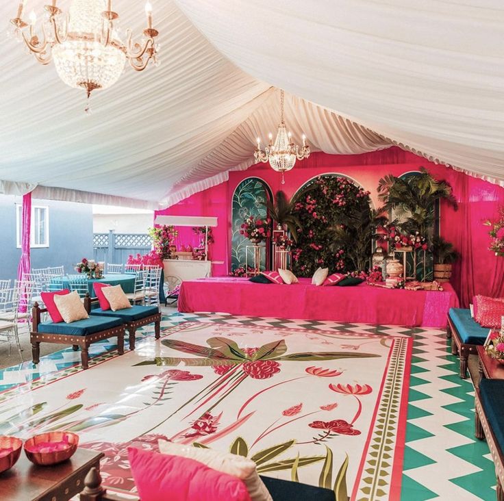 a pink and white room with couches, tables and chandelier hanging from the ceiling