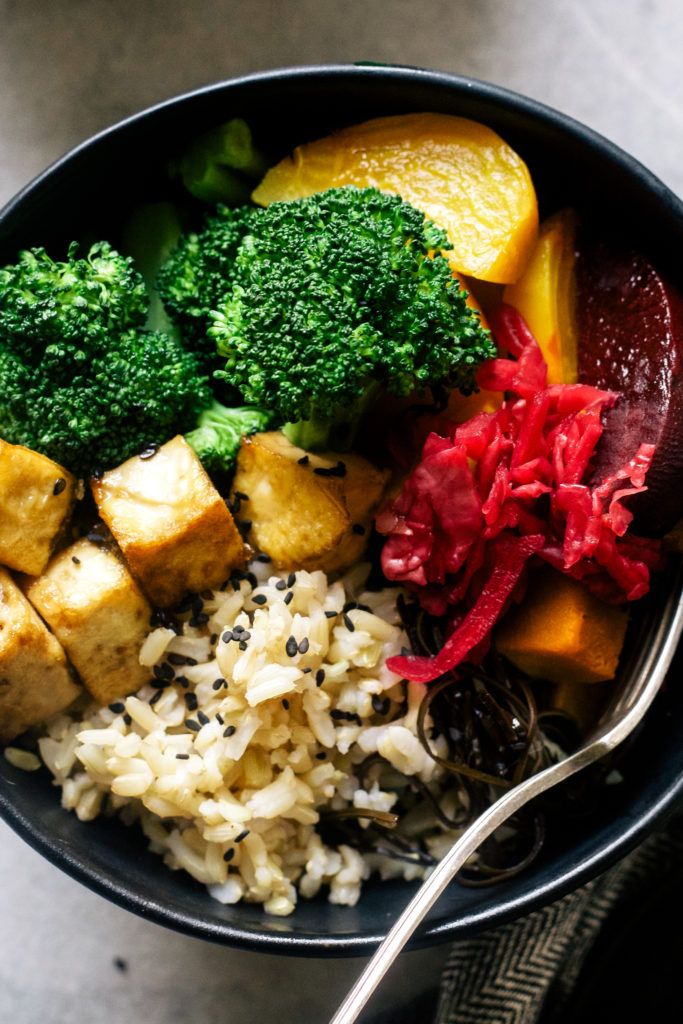 a bowl filled with rice, broccoli and tofu on top of it