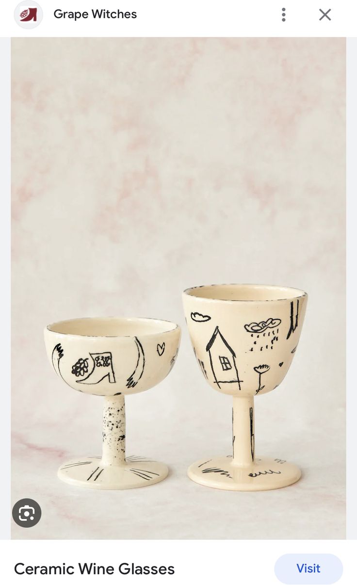 two white bowls with designs on them sitting next to each other in front of a pink wall