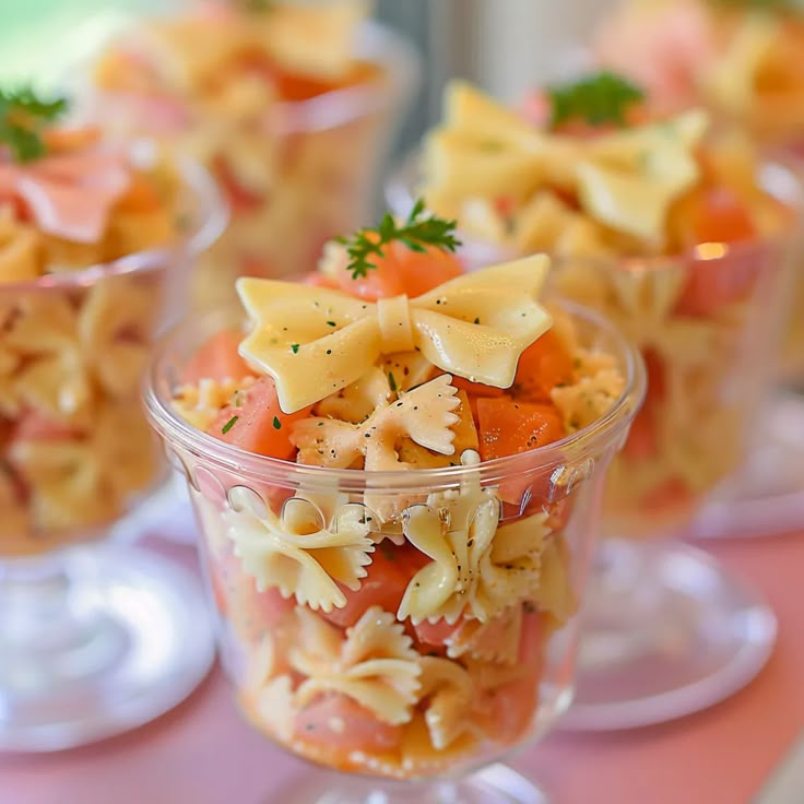 small bowls filled with pasta and vegetables on top of a pink tablecloth covered table