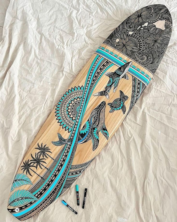 a wooden surfboard laying on top of a bed next to some crayons