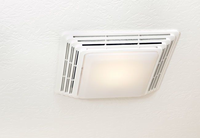 an air conditioner mounted on the side of a white wall with a light in it