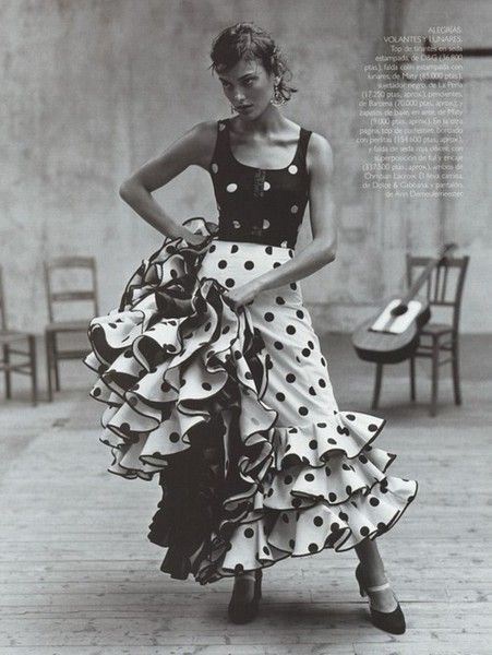 a black and white photo of a woman in a polka dot dress with her hands on her hips