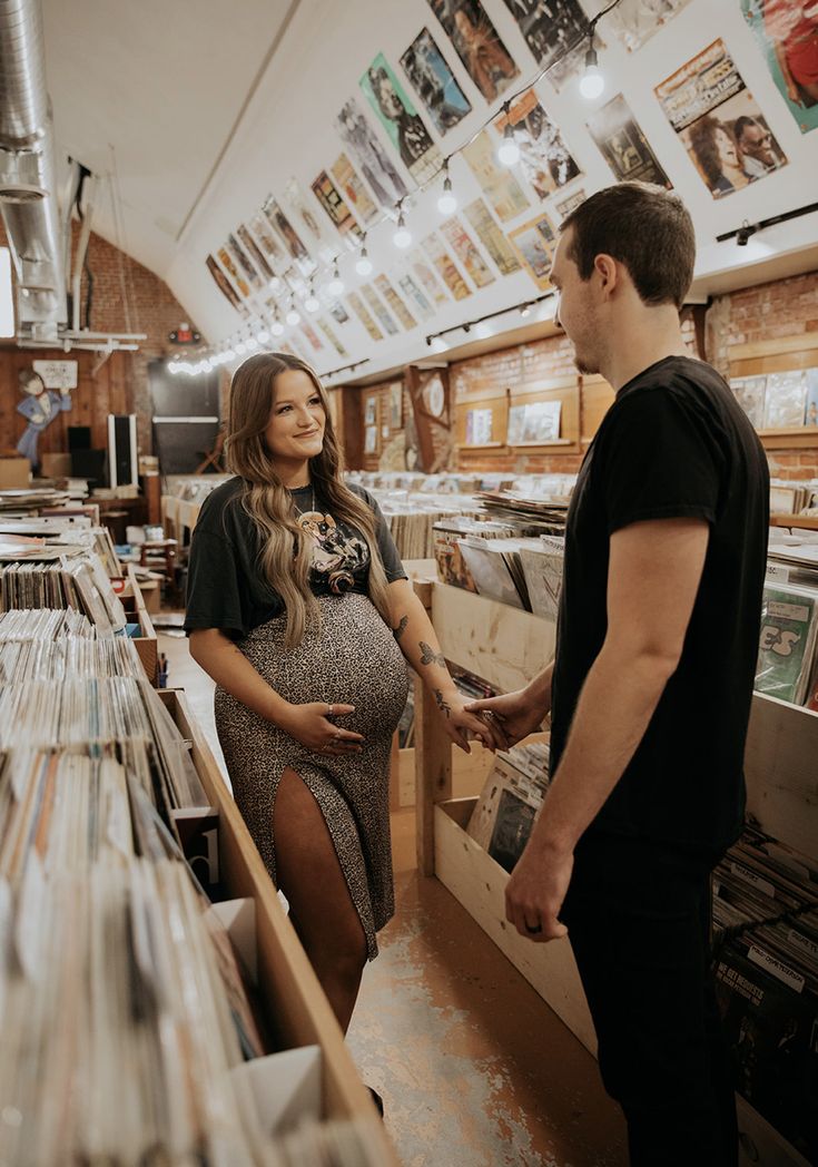 a pregnant woman standing next to a man in a record store