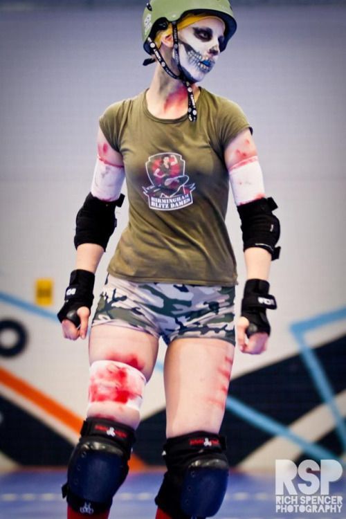 a female rollerblader with paint all over her body and knee pads is walking