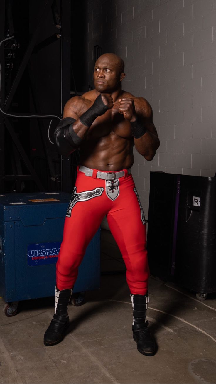 a man in red pants and black boots is posing with his hands on his hips