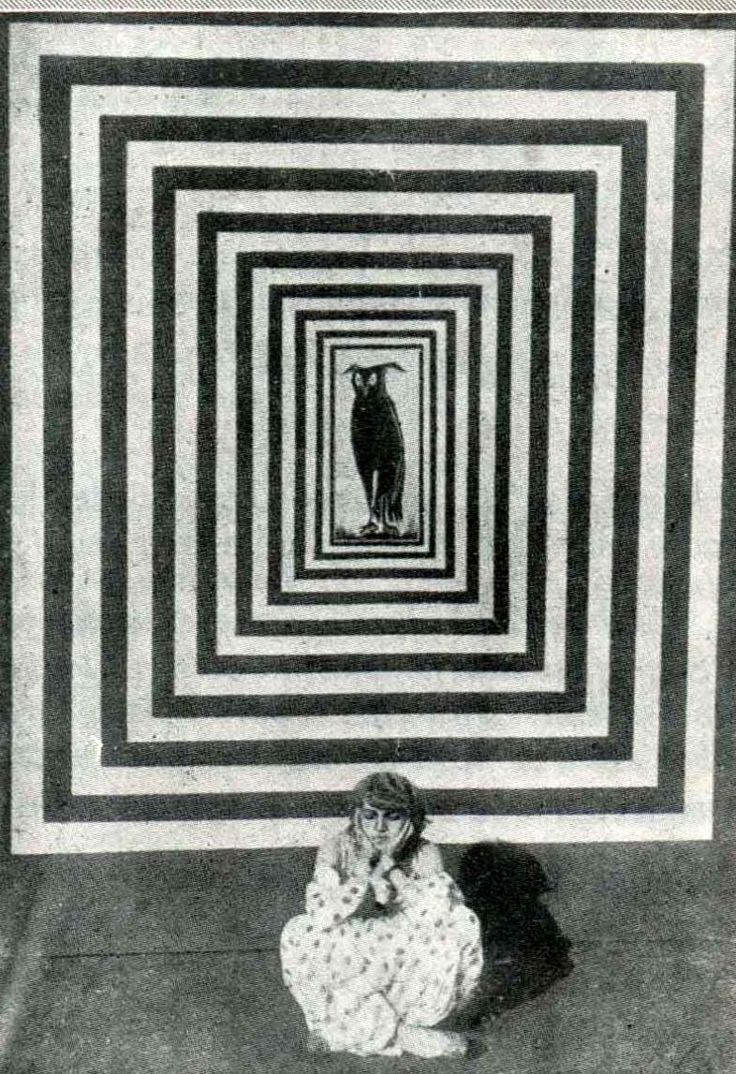 a woman sitting on the floor in front of a black and white square with a dog