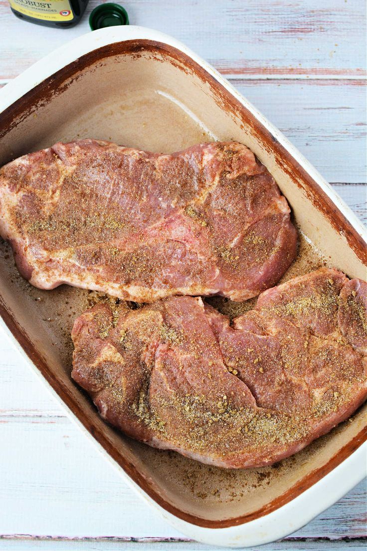 two steaks in a baking dish with seasoning