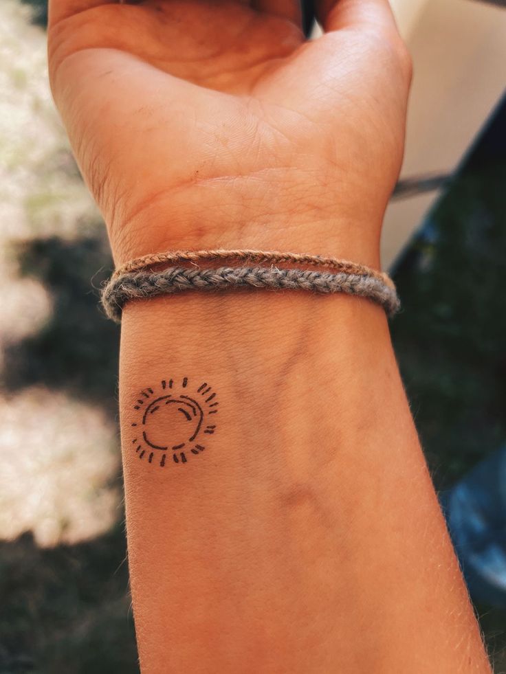 a person's wrist with a small tattoo on the left side of their arm