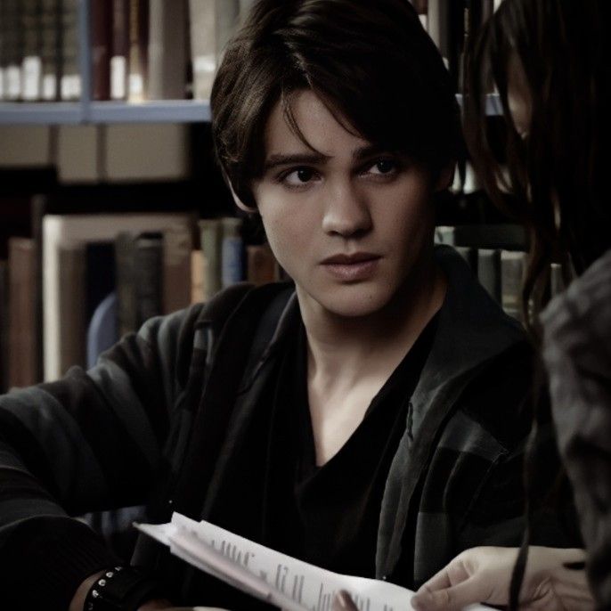 a woman sitting in front of a bookshelf holding a piece of paper