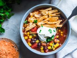 a bowl of mexican soup with corn, beans and tortilla chips on the side