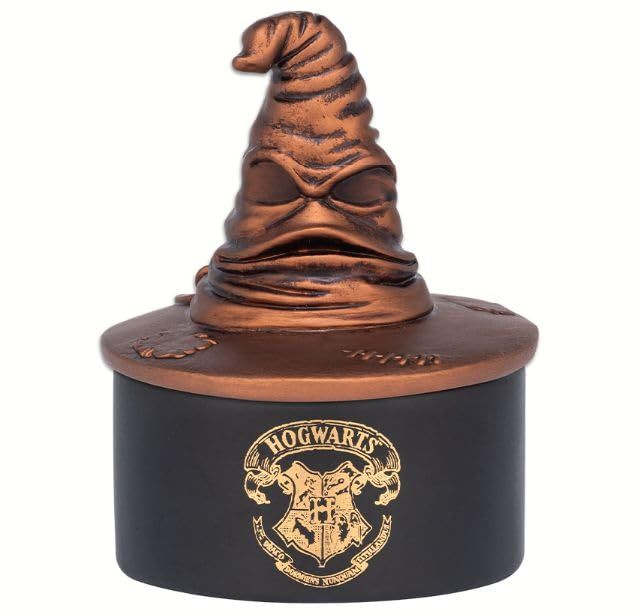 a harry potter hat on top of a black and gold container with the hogwarts crest