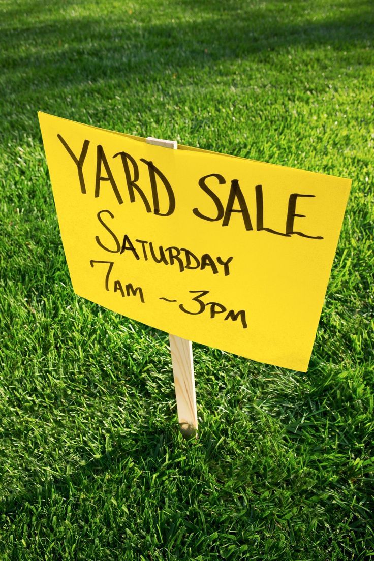 a yard sale sign sitting in the grass