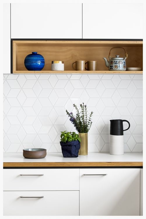 a kitchen with white cupboards and shelves filled with pots, plants and vases