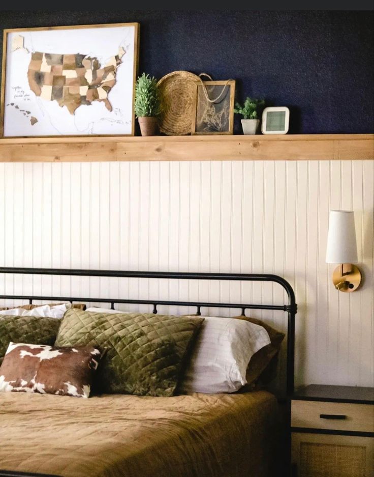 a bed sitting under a wooden shelf next to a wall mounted art above it's headboard