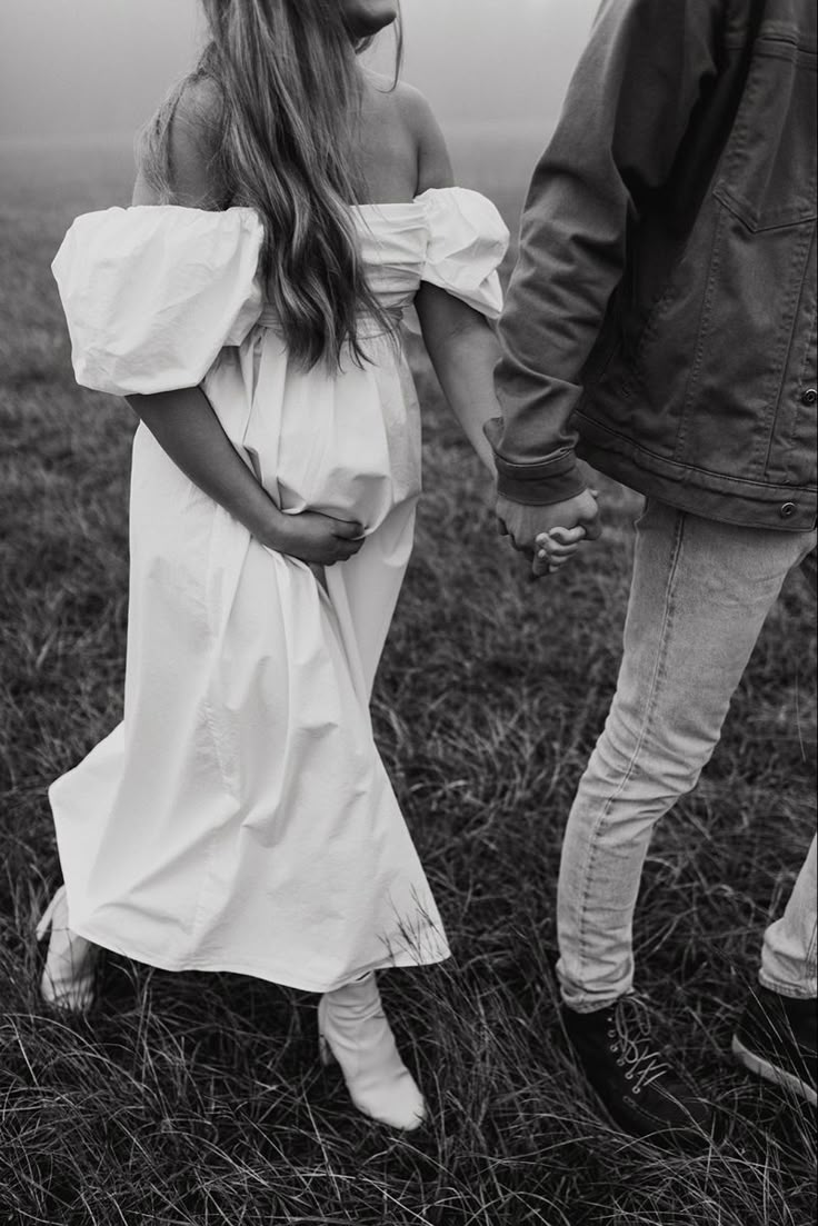 black and white photograph of a woman in a dress holding the hand of a man