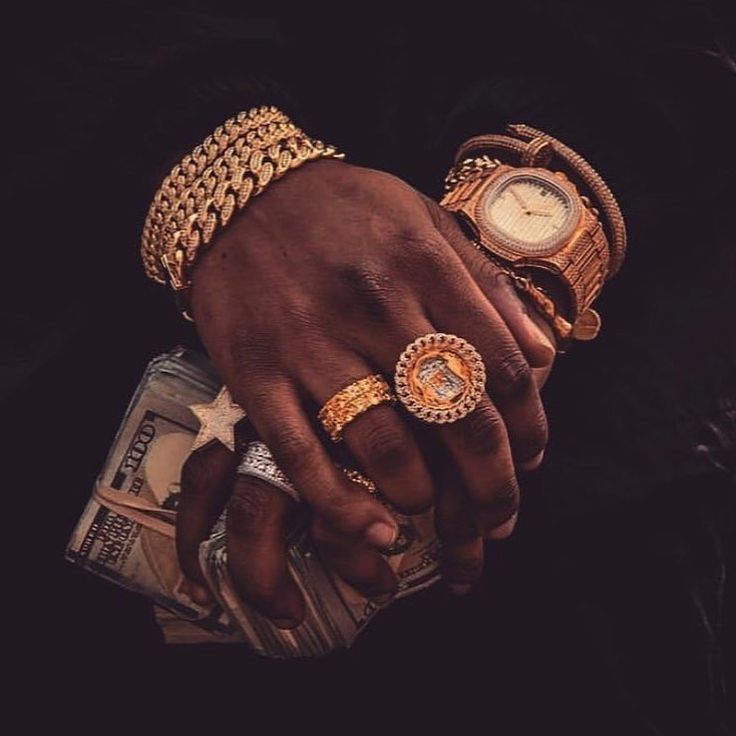 a person holding money in their hand with two rings on it's wrist and wearing gold bracelets