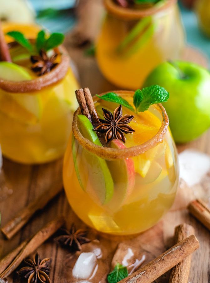 two glasses filled with apple cider and cinnamon stick garnished with star anise