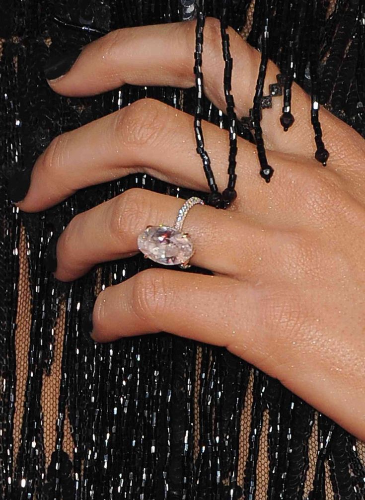 a woman's hand with a ring on it and a black beaded dress