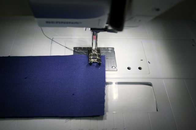 the sewing machine is working on the blue piece of fabric that has been sewn