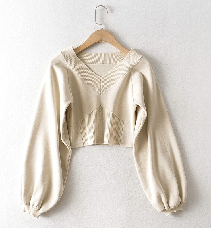 The Cream Balloon Sleeve Knit Sweater is a stylish addition to any wardrobe, offering a blend of comfort and contemporary fashion. This sweater features an elegant V-neckline and unique geometric ribbed detailing on the front, adding a touch of sophistication to its casual appeal. The soft cream color makes it versatile and easy to pair with a variety of outfits, whether youre dressing up for a day out or keeping it cozy at home.Crafted from high-quality knit fabric, this sweater ensures a comfo Beige Knit V-neck Cardigan, Trendy Ribbed V-neck Cardigan, Fitted V-neck Sweater For Fall, Fitted Ribbed V-neck Sweater With Long Sleeves, Stretch Ribbed V-neck Sweater, Trendy Fitted V-neck Sweater For Fall, Fitted Long Sleeve V-neck Sweater For Fall, Knitted V-neck Sweater For Winter, Beige Knit V-neck Sweater For Fall