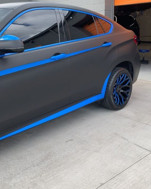 a gray and blue car parked in front of a garage